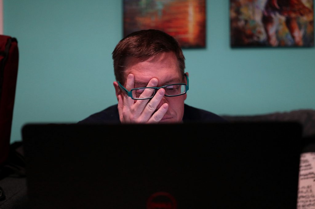 Exhausted man at a computer rubbing his eyes